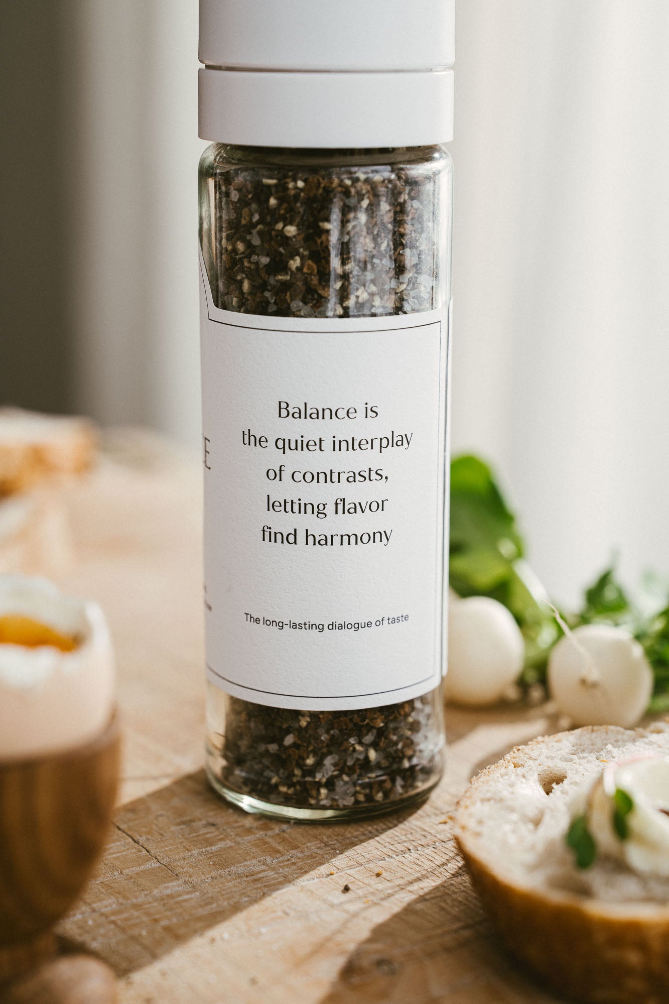 Spice grinder with a label on a wooden surface with food items