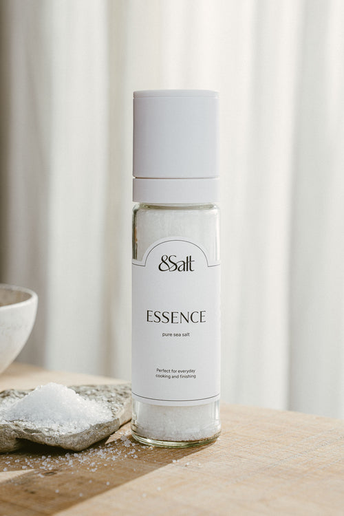 Bottle of '&Salt' Essence on a wooden surface with a neutral background